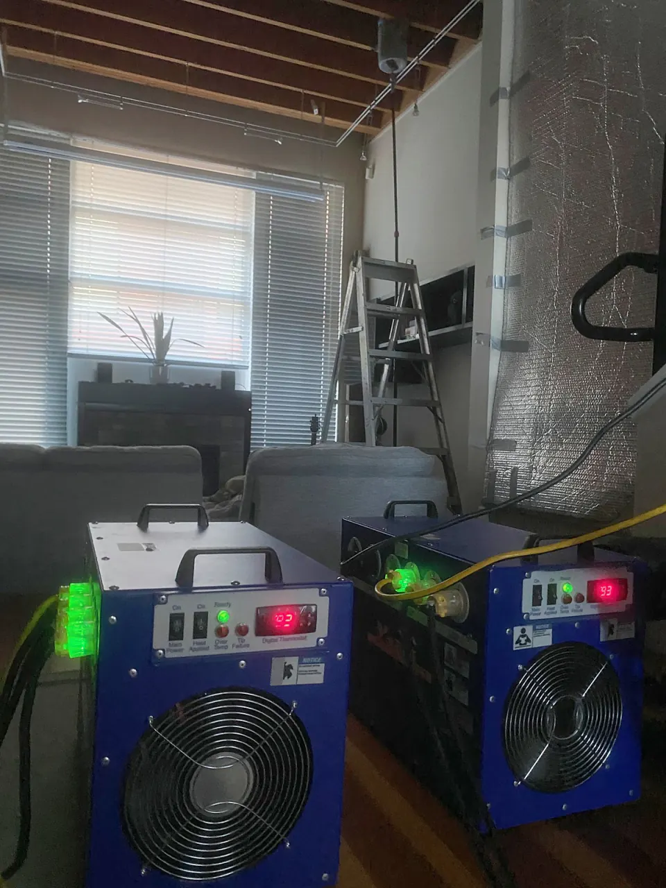 Two electric bed bug heaters running in a living room during a heat treatment
